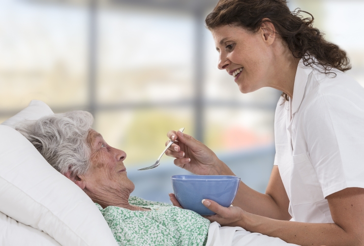 caregiver feeding elderly woman