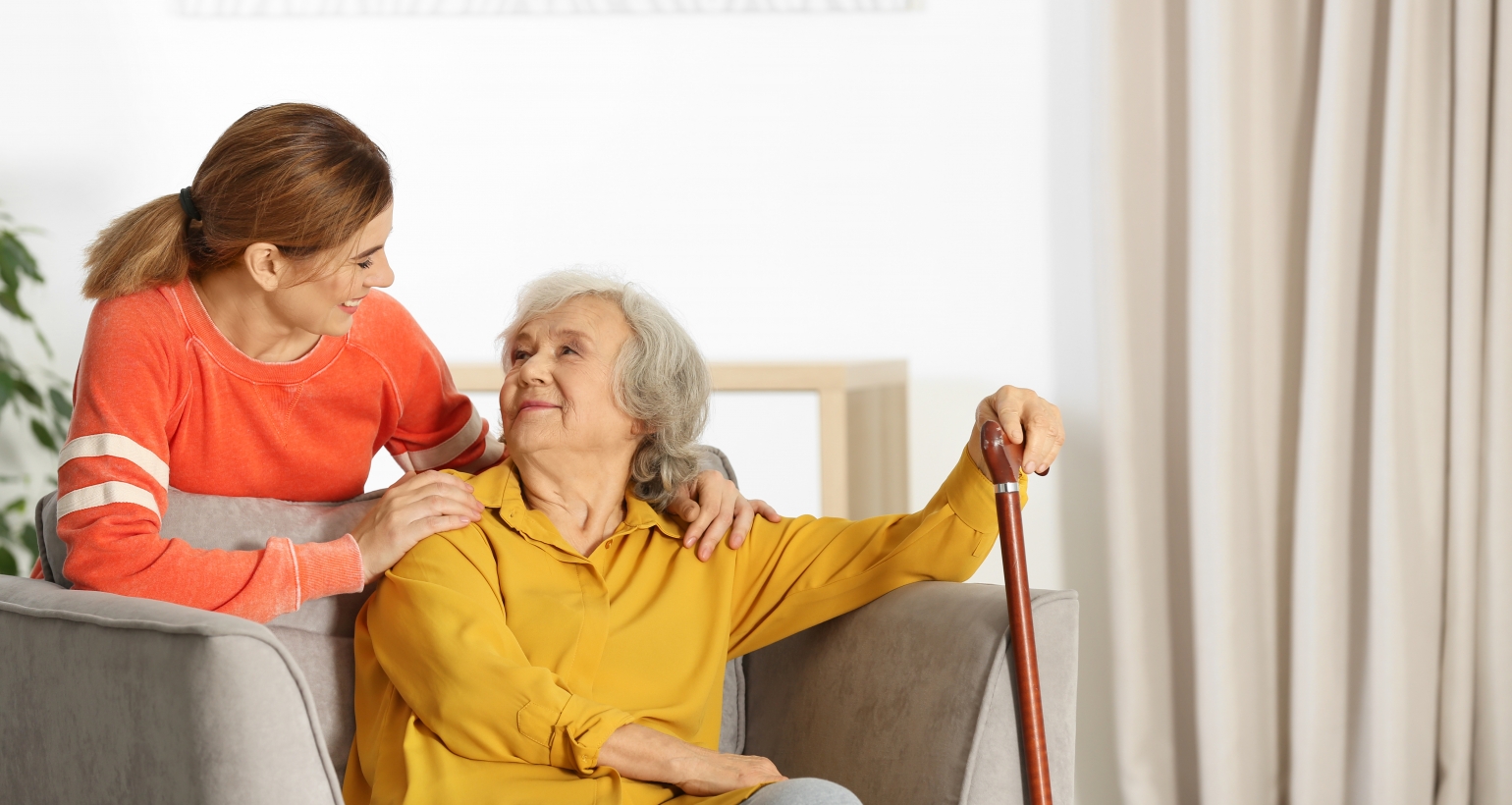 Elderly woman with female caregiver in living room