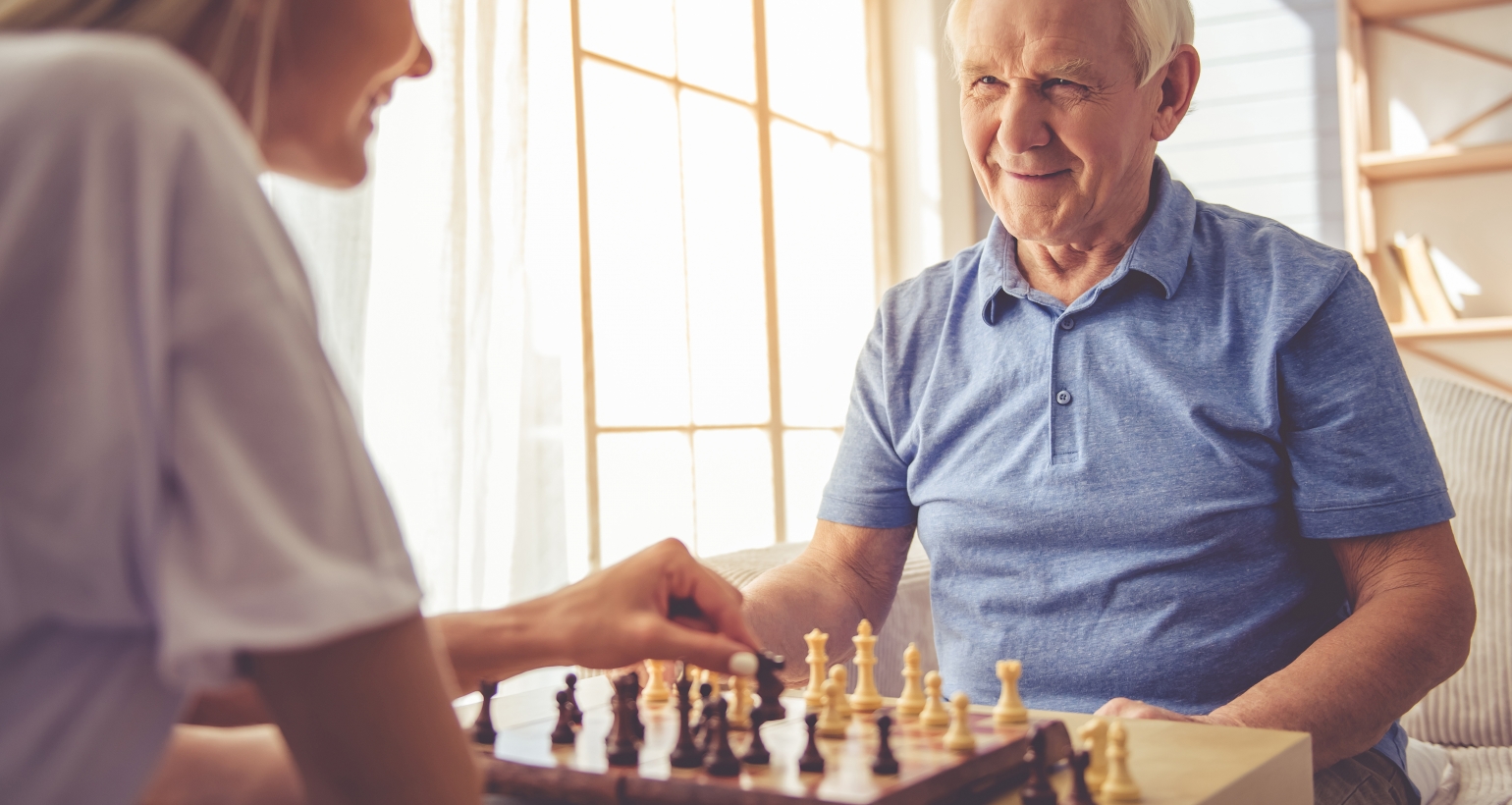 elderly man playing chess with his caregiver